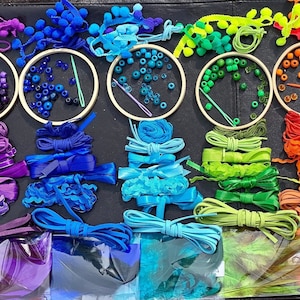 May include: A rainbow of craft supplies for making jewellery and accessories. The supplies include beads, ribbon, yarn, and pom-poms in shades of purple, blue, green, and orange.