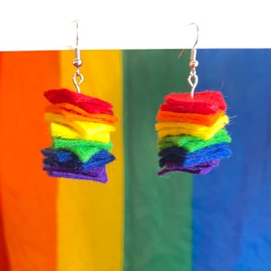 May include: Rainbow-colored felt star earrings. Each earring is made of six stacked felt stars in the colors of the rainbow: red, orange, yellow, green, blue, and purple.