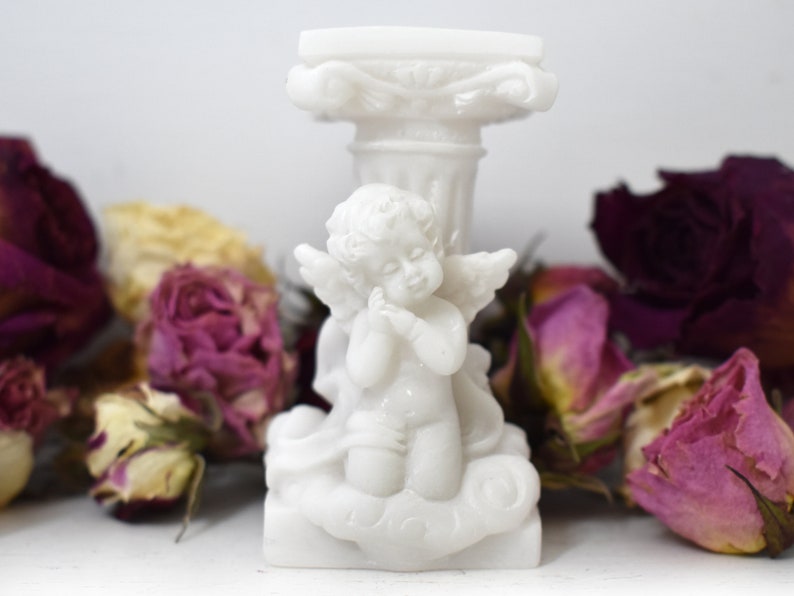 K&ouml;nnte beinhalten: Wei&szlig;e Porzellanfigur eines Cherubins mit Fl&uuml;geln, kniend auf einer Wolke, auf einem wei&szlig;en Sockel mit dekorativem Sockel.