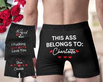 May include: Black boxer briefs with white text that reads "THIS ASS BELONGS TO: Charlotte" and red heart accents. Other briefs have phrases like "Kissed it... So it's" and "I Fucking Love You".