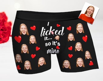 May include: Black boxer shorts with a repeated pattern of red hearts and faces. The text "I licked it... so it's mine" is printed in white on the front.