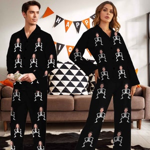 May include: A couple wearing black pajamas with a skeleton print featuring their faces. The pajamas have a button-up front and long sleeves. The background is a black and white checkered pattern.
