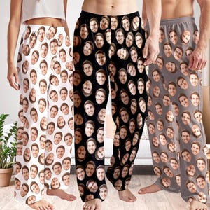 May include: Three pairs of pajama pants with a repeating pattern of a person's face. The pants are in white, black, and gray. The white pants have a brown face pattern, the black pants have a brown face pattern, and the gray pants have a brown face pattern.