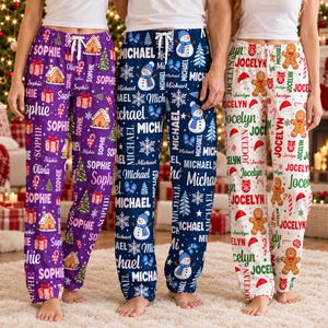 May include: Three pairs of pajama pants with drawstring waists. The purple pair features gingerbread houses and the name Sophie. The blue pair features snowmen and the name Michael. The white pair features gingerbread men and the name Jocelyn.