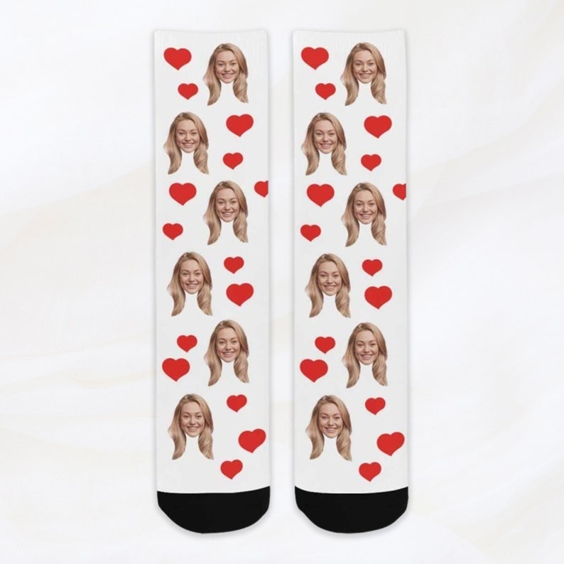 May include: A pair of white socks with a repeating pattern of red hearts and a woman's face.