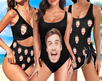 May include: Black swimsuits with a repeating pattern of a man's face. One-piece and two-piece swimsuits are shown. The swimsuits have a scoop neck and are made of a stretchy material. The background shows a beach scene.