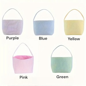 May include: Five Easter baskets in different colors: purple, blue, yellow, pink, and green. Each basket has a white handle and is made of a striped fabric.