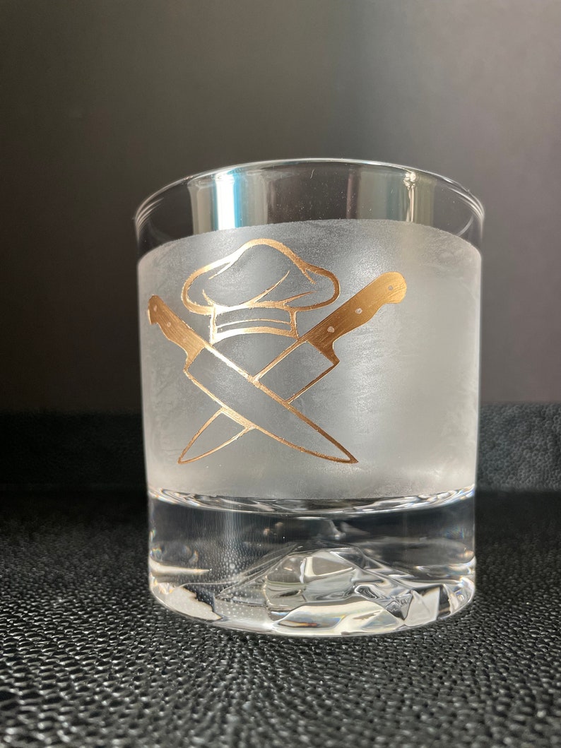 May include: A frosted glass with a gold design of crossed chef's knives and a chef's hat.