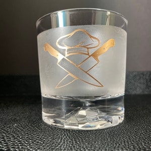 May include: A frosted glass tumbler with a gold chef's hat and crossed knives design.