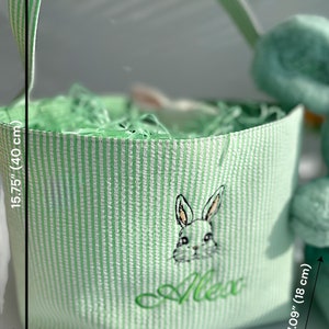 May include: Green and white striped Easter basket with a green bunny and the name "Alex" embroidered on the front. The basket is 15.75 inches tall and 7.87 inches wide.
