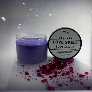 May include: A purple body scrub jar with a black lid and white text that reads "DSCRUBS LOVE SPELL BODY SCRUB MADE WITH 100% ORGANIC INGREDIENTS FOAMING BATH BUTTER BASE, FRAGRANCE OIL, MICA POWDER, SUGAR, ORGANIC OILS NET WT 4 OZ".