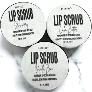 Puede incluir: Tres peque&ntilde;os frascos de exfoliante labial con etiquetas blancas. Las etiquetas tienen texto negro que dice "Lip Scrub" y el sabor de cada exfoliante: "Strawberry", "Cake Batter" y "Vanilla Bean". Cada frasco tiene un peso neto de 1,3 oz.