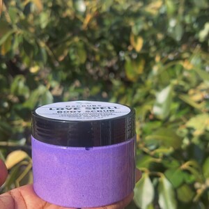 May include: A purple jar of body scrub labeled "Love Spell Body Scrub".
