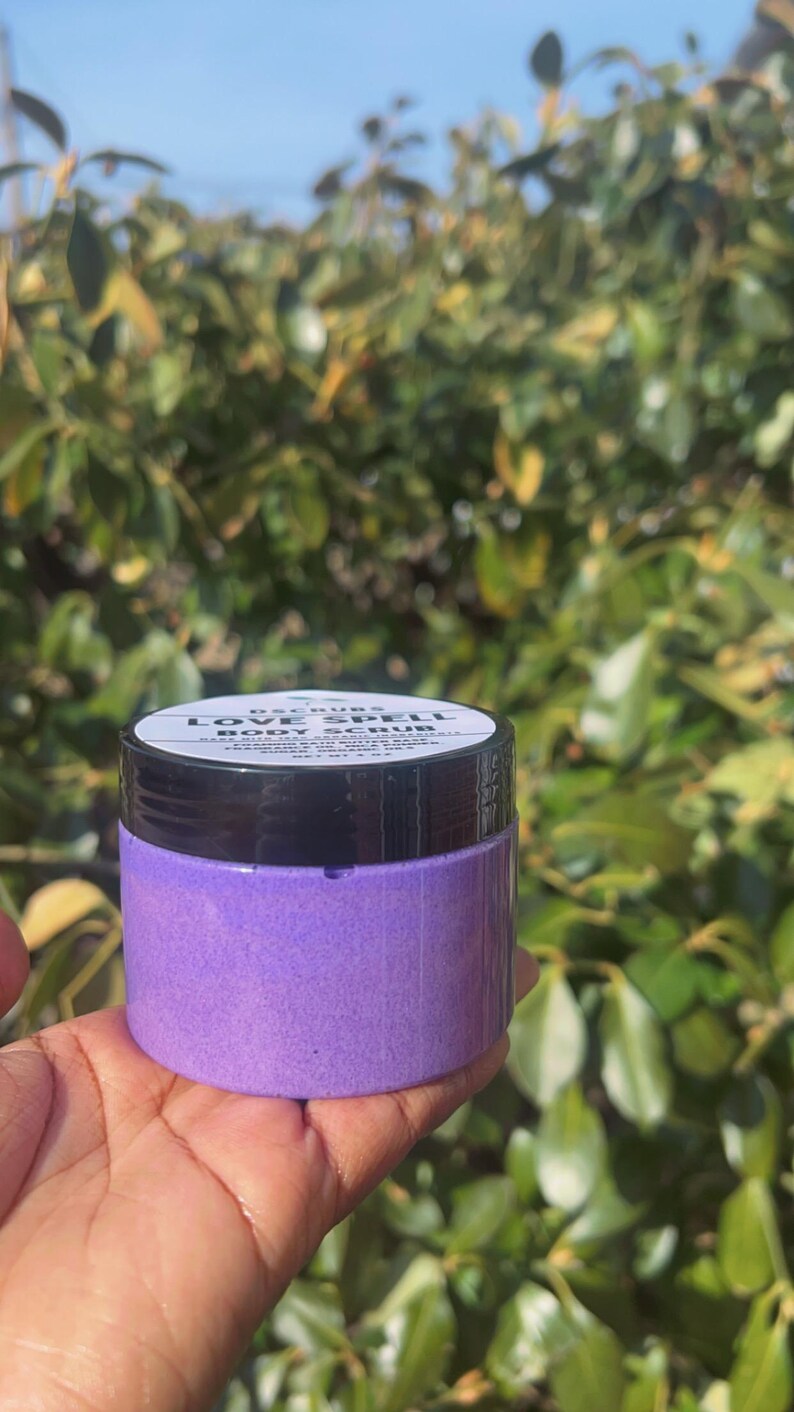 May include: A purple jar of body scrub labeled "Love Spell Body Scrub".