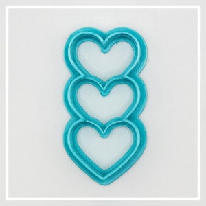 May include: A turquoise blue cookie cutter shaped like three stacked hearts.