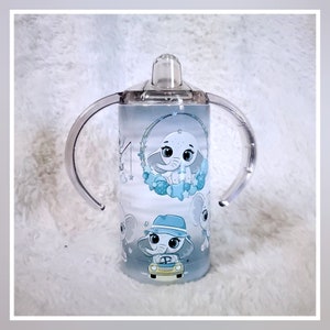 May include: A blue and white stainless steel tumbler with a clear lid and two handles. The tumbler features a design of an elephant with stars and a baby elephant in a car.