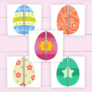 May include: Five colorful Easter egg designs on white cards. The eggs feature various patterns, including stripes, floral, and geometric shapes, in shades of blue, green, pink, orange, and yellow. Each card is split down the middle with a dashed line.