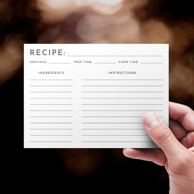 May include: A blank white recipe card with the word "RECIPE" at the top. The card is divided into two sections, one for ingredients and one for instructions. There are lines for writing down the recipe details, including servings, prep time, and cook time.