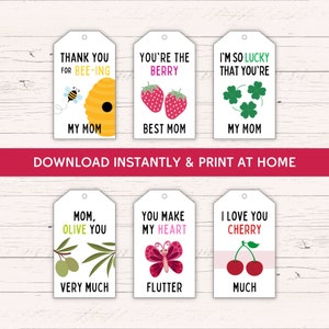 May include: Six printable gift tags with cute illustrations and puns for Mother's Day. The tags feature a bee, strawberries, shamrocks, olives, a butterfly, and cherries. The text on the tags includes "Thank you for bee-ing my mom", "You're the berry best mom", "I'm so lucky that you're my mom", "Mom, olive you very much", "You make my heart flutter", and "I love you cherry much".
