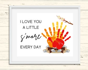 May include: A white framed print with the text "I love you a little s'more every day" and a handprint illustration of a campfire with marshmallows.