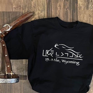 May include: Black t-shirt with a white graphic of a horse running with the text "LEG >>  15-Mile, Wyoming" printed on the front.