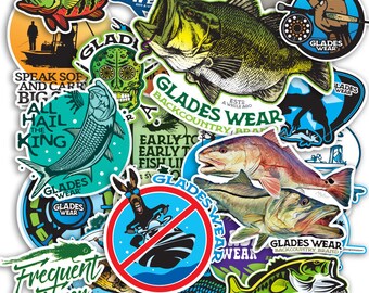 May include: A collection of colorful fishing-themed stickers featuring various fish illustrations, logos, and text. The stickers include images of bass, redfish, and other aquatic life, with phrases like "Glades Wear" and "Backcountry Brand".