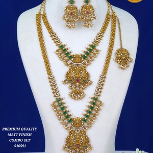 Può includere: Un set di gioielli color oro composto da due collane a strati, orecchini pendenti abbinati e un maang tikka. I pezzi sono decorati con pietre rettangolari verdi, piccole perline bianche e intricati motivi di divinità in rilievo. Testo: PREMIUM QUALITY MATT FINISH COMBO SET 910591.