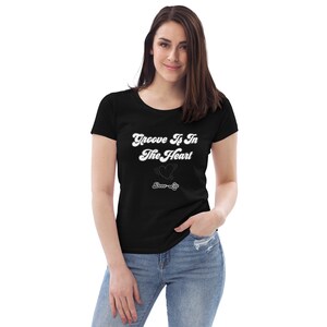 May include: A black t-shirt with a white graphic that says "Groove Is In The Heart" with a heart and the words "Dance-Life" underneath.