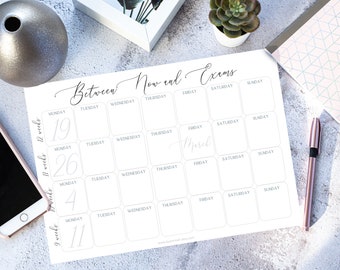 May include: A white paper planner with the text "Between Now and Exams" in elegant script. The planner features a calendar layout with numbered weeks and days of the week, perfect for scheduling and organization.