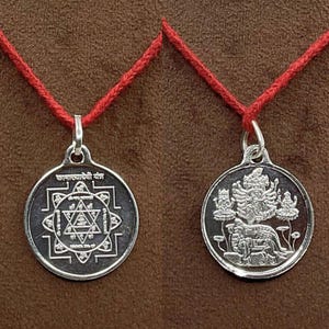 Pode incluir: Dois pingentes de prata com cordões vermelhos. Um apresenta um design geométrico com texto, o outro retrata uma divindade com um leão. Ambos são redondos e têm uma argola para o cordão.