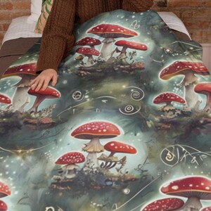 May include: A green and white blanket with a repeating pattern of red and white mushrooms. The mushrooms are surrounded by swirling lines and dots. The blanket is made of soft, comfortable fabric.
