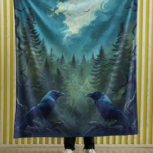 May include: A blue fleece blanket with a dark forest scene and two black ravens. The forest is filled with tall, dark green trees and a swirling blue sky. The ravens are facing each other, perched on branches.