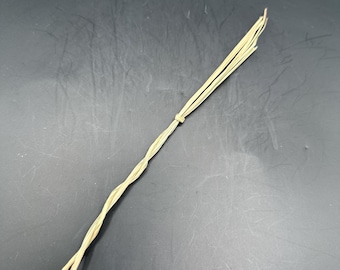 May include: A long, thin, braided cord made of natural fibers. The cord is light brown in color and has a slightly rough texture.