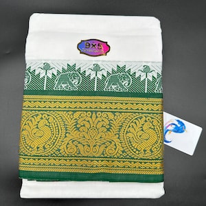 Op de afbeelding: Witte katoenen stof met een groene rand met een herhalend patroon van olifanten en bloemenmotieven. De rand heeft ook een gouden bies. De stof heeft een label met de tekst "9x5 Special Quality."