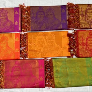 Pode incluir: Um conjunto de oito lenços de seda coloridos com uma imagem impressa de um casal. Os lenços são decorados com guarnições douradas e borlas.
