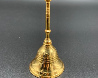 May include: A gold-colored bell with a rounded top and a handle. The bell has a smooth, shiny surface.
