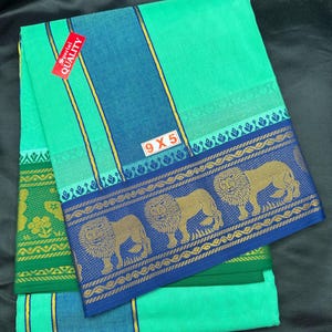 Op de afbeelding: Een gevouwen groene en blauwe katoenen sari met een gouden en blauwe rand met een herhalend patroon van leeuwen. De sari heeft een label met de tekst "Special Quality" en "9x5".