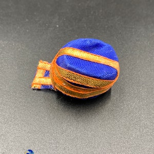 Peut inclure: Un petit turban bleu et or avec un motif décoratif. Le turban est fait de tissu et a une surface douce et texturée.