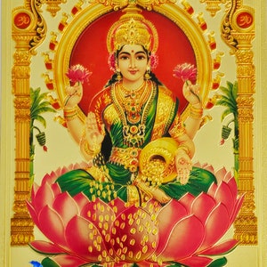 Peut inclure: Une image dorée de Lakshmi, la déesse hindoue de la richesse et de la prospérité. Elle est représentée assise sur une fleur de lotus rose, tenant un pot de pièces d'or dans une main et une fleur de lotus dans l'autre. L'image est entourée d'un cadre doré et porte le texte "J.B. Khanna Pictures" en bas.
