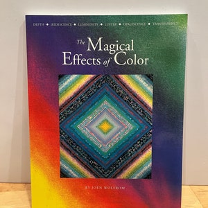 May include: The cover of a book titled "The Magical Effects of Color" by Joen Wolffrom. The cover features a colorful, geometric design with a diamond shape in the center.