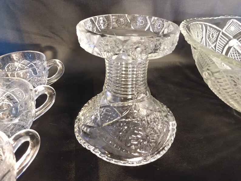 Puede incluir: Un juego de ponchera de cristal transparente con base de pedestal y cuatro tazas. La ponchera y las tazas tienen un dise&ntilde;o de cristal tallado.