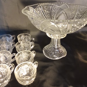 Puede incluir: Un juego de ponchera de cristal vintage con un cuenco grande y transparente con base de pedestal y ocho tazas a juego. El cuenco y las tazas tienen un dise&ntilde;o de cristal tallado.