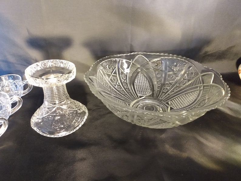 Puede incluir: Un juego de ponchera de cristal vintage con un cuenco grande y transparente con borde festoneado y un dise&ntilde;o de cristal tallado intrincado. El juego tambi&eacute;n incluye una base de pedestal y cuatro tazas, todas con patrones de cristal tallado a juego.
