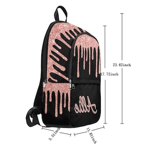 May include: Black backpack with a rose gold glitter drip design. The backpack has a zippered pocket on the front and the name "Aila" written in rose gold glitter. The backpack measures 17.72 inches tall, 11.81 inches wide, and 5.51 inches deep.