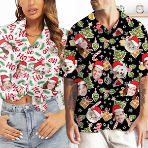 May include: A pair of matching Christmas-themed button-up shirts with a white background and a black background. The shirts feature a repeating pattern of Christmas trees, baubles, candy canes, and holly. The shirts also feature a variety of faces, including people and animals, wearing Santa hats.
