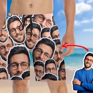 May include: A pair of men's swim trunks with a pattern of repeated faces. The faces are all of the same person, and they are arranged in a random pattern. The trunks are white with a black drawstring.
