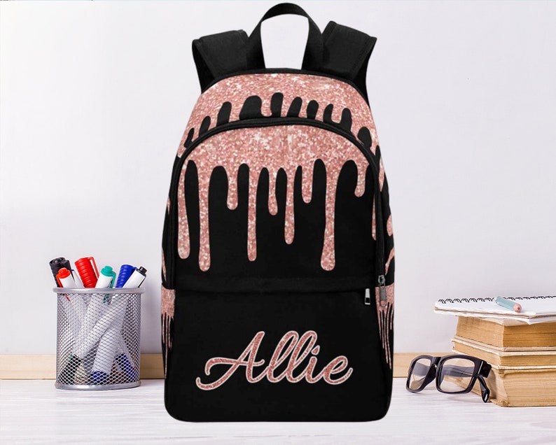 May include: Black backpack with a pink glitter drip design and the name "Allie" written in pink glitter on the front.