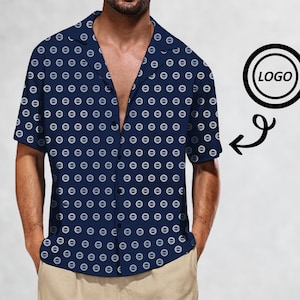 May include: A navy blue short-sleeved button-down shirt with a white geometric pattern. The shirt has a collar and a button closure. The shirt is shown on a model. The image also includes a black circle with the word "LOGO" in white text.
