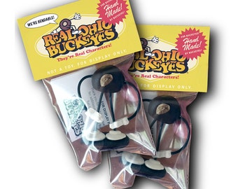 May include: Two packages of bendable, hand-made Ohio State Buckeye figurines. The packages are yellow with black lettering and say "Real Ohio Buckeyes" and "They're Real Characters! Not a toy. For display only."