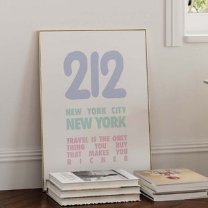 Puede incluir: Una impresión enmarcada con un marco dorado y un fondo blanco. La impresión presenta el texto "212 New York City New York Travel is the only thing you buy that makes you richer".